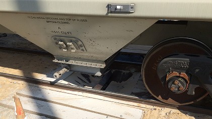 Unloading a railcar with an under rail unloading conveyor.